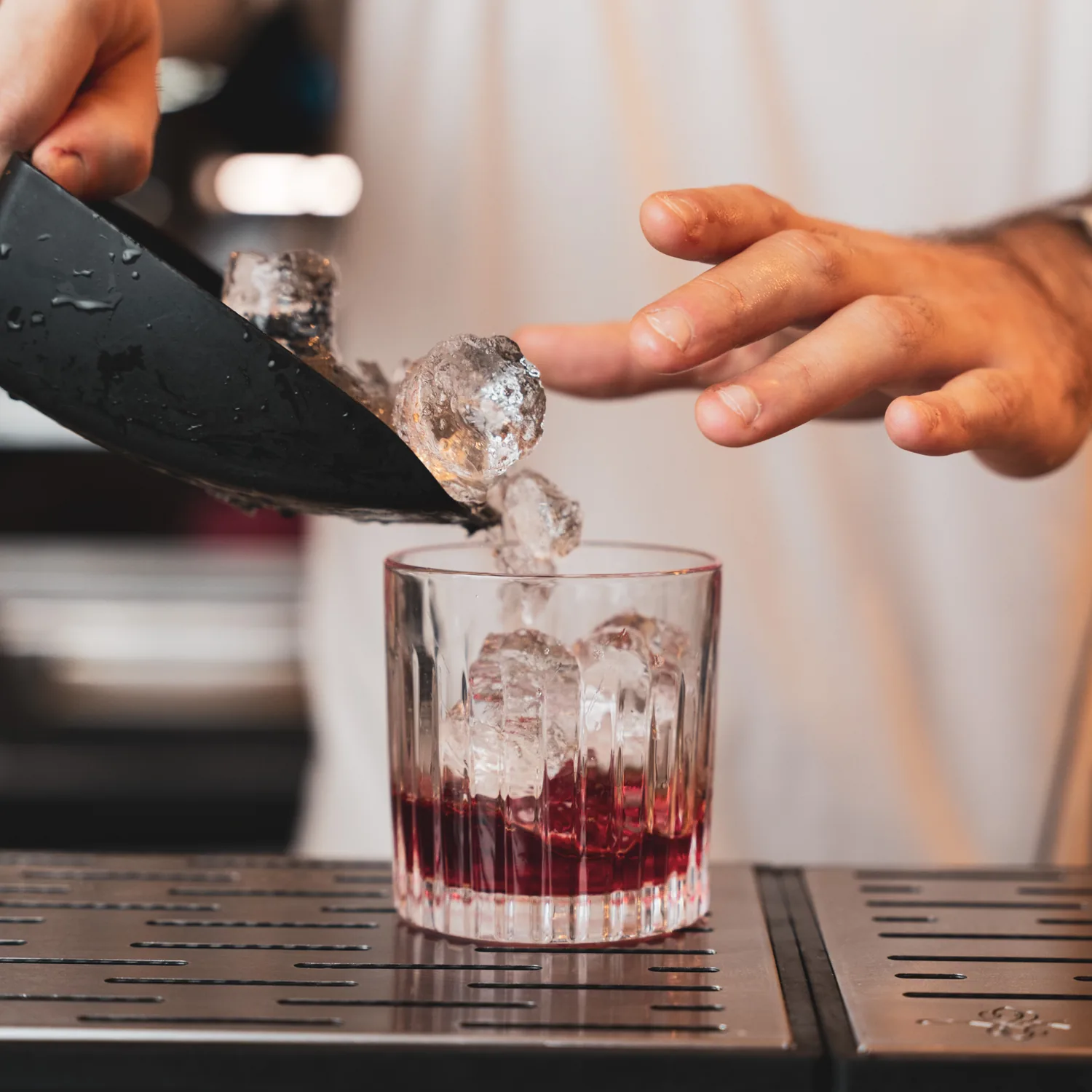 Il barman versa il ghiaccio in un tumbler per un cocktail