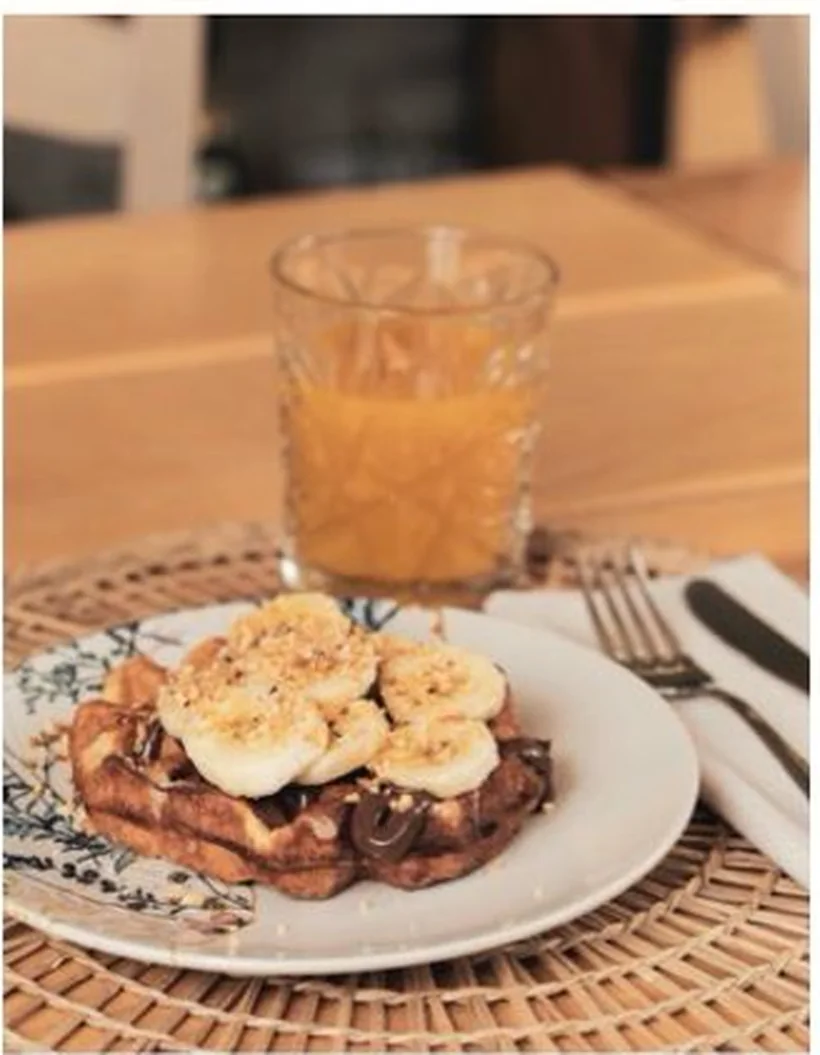 Waffle con banana e nocciole accanto a una spremuta